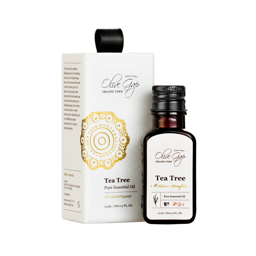 15ml glass bottle of certified organic pure essential tea tree oil by Olive Gap Farm next to a white box made of cardboard with indigenous design in gold by local indigenous artist