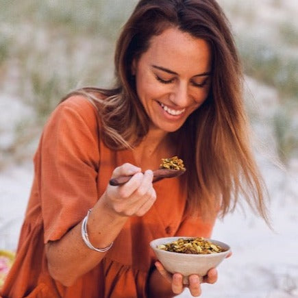 Woman holding spoon over bowl of golden granola 