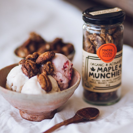 Bowl of ice cream topped with Maple nuts with glass jar of Organic Maple Munchies next to it