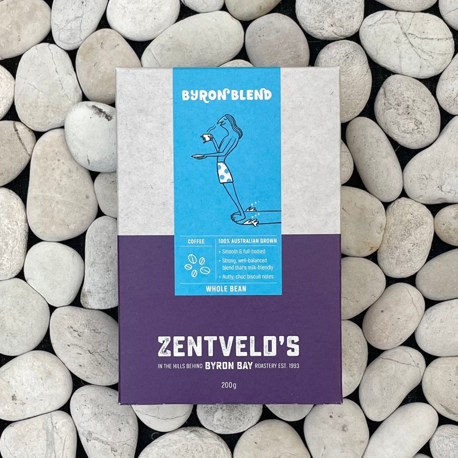 200g box of Zentveld's Byron Blend coffee with caricature of a surfer on the board drinking coffee. Background are whitish grey stones